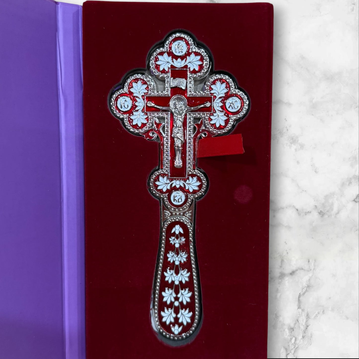 Double-sided red and white enamel blessing cross with metal crucifix displayed inside a premium gift box.