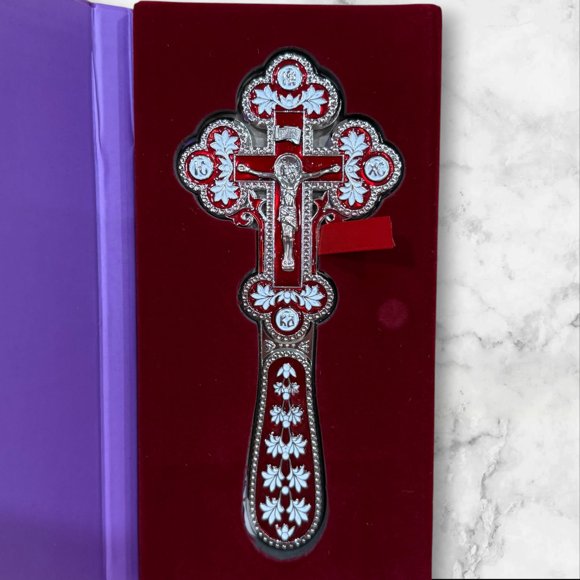 Double-sided red and white enamel blessing cross with metal crucifix displayed inside a premium gift box.