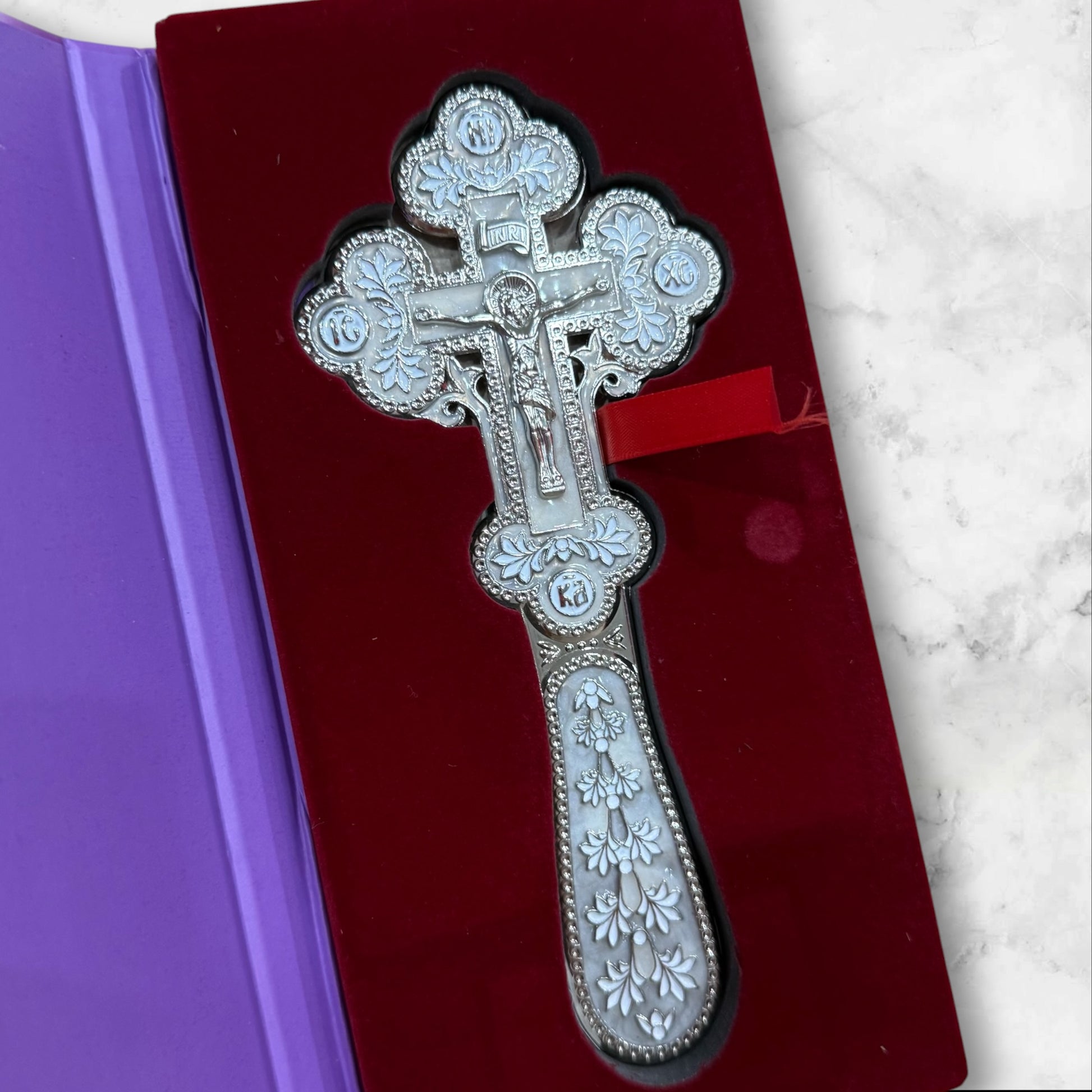 white enamel blessing cross with metal crucifix displayed inside a premium gift box.