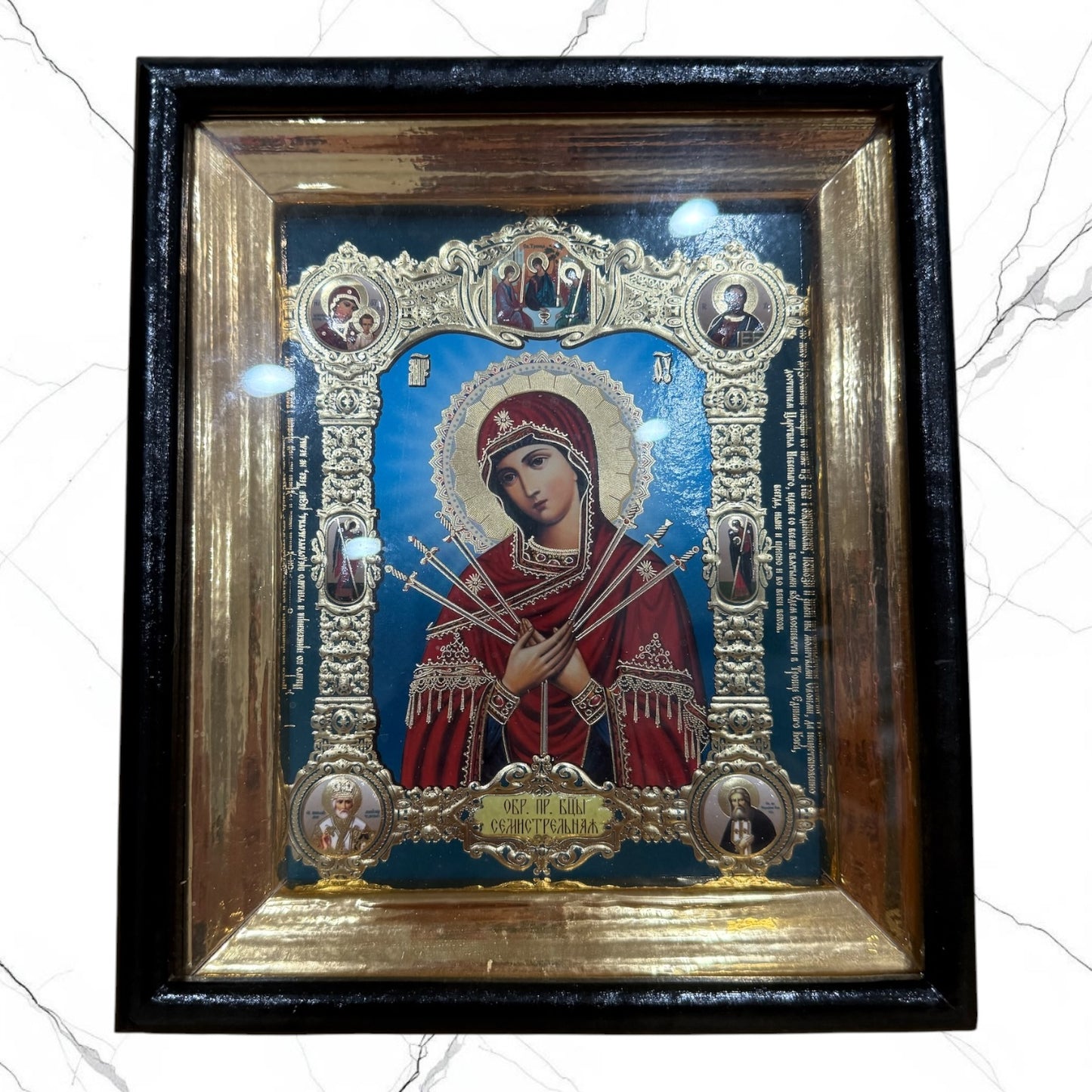 Framed icon of the Mother of God Seven Swords with decorative metallic embellishments beneath glass.