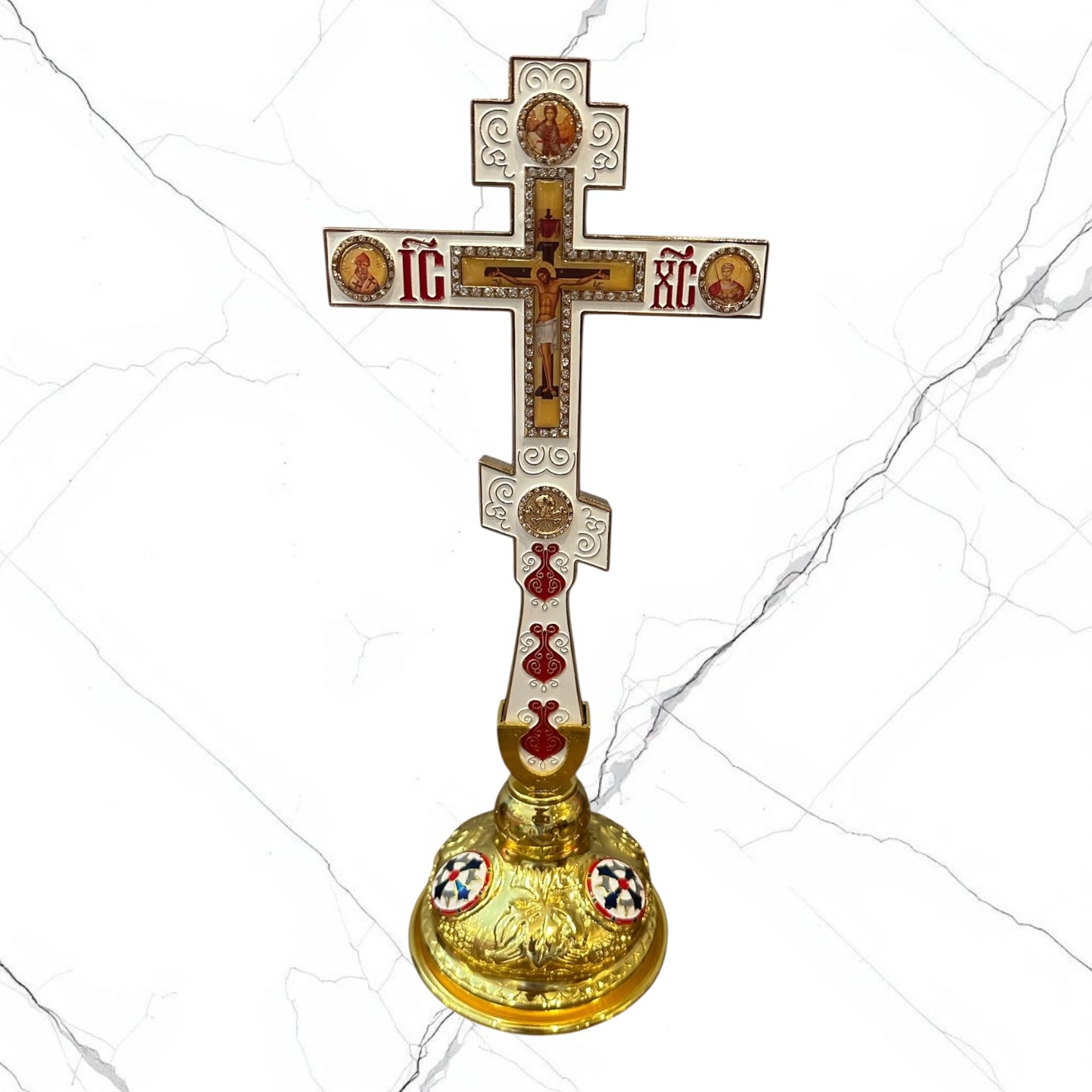 White enamel Orthodox standing blessing cross with ornate gold-tone base.