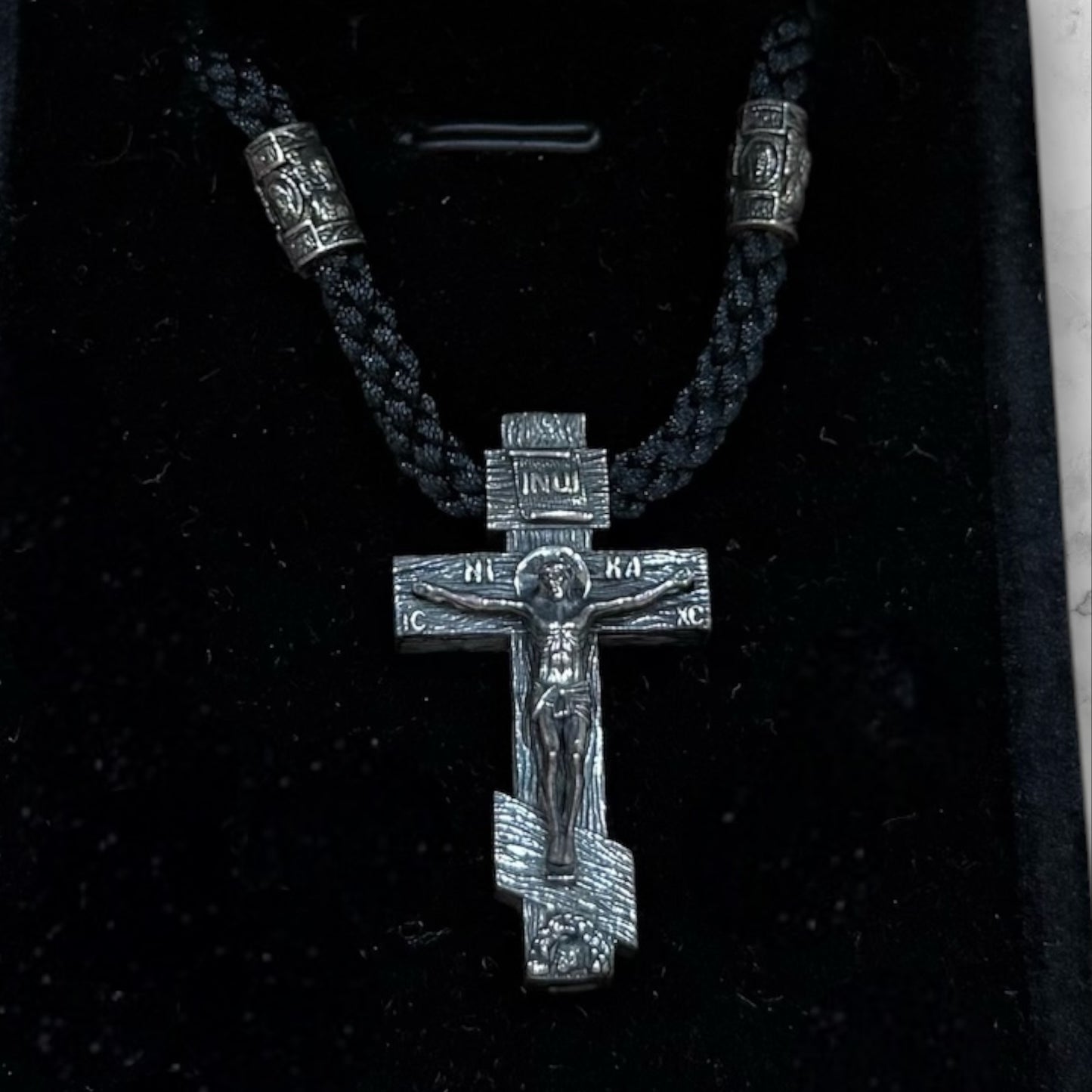 Orthodox crucifix pendant with braided black cord displayed in a gift box
