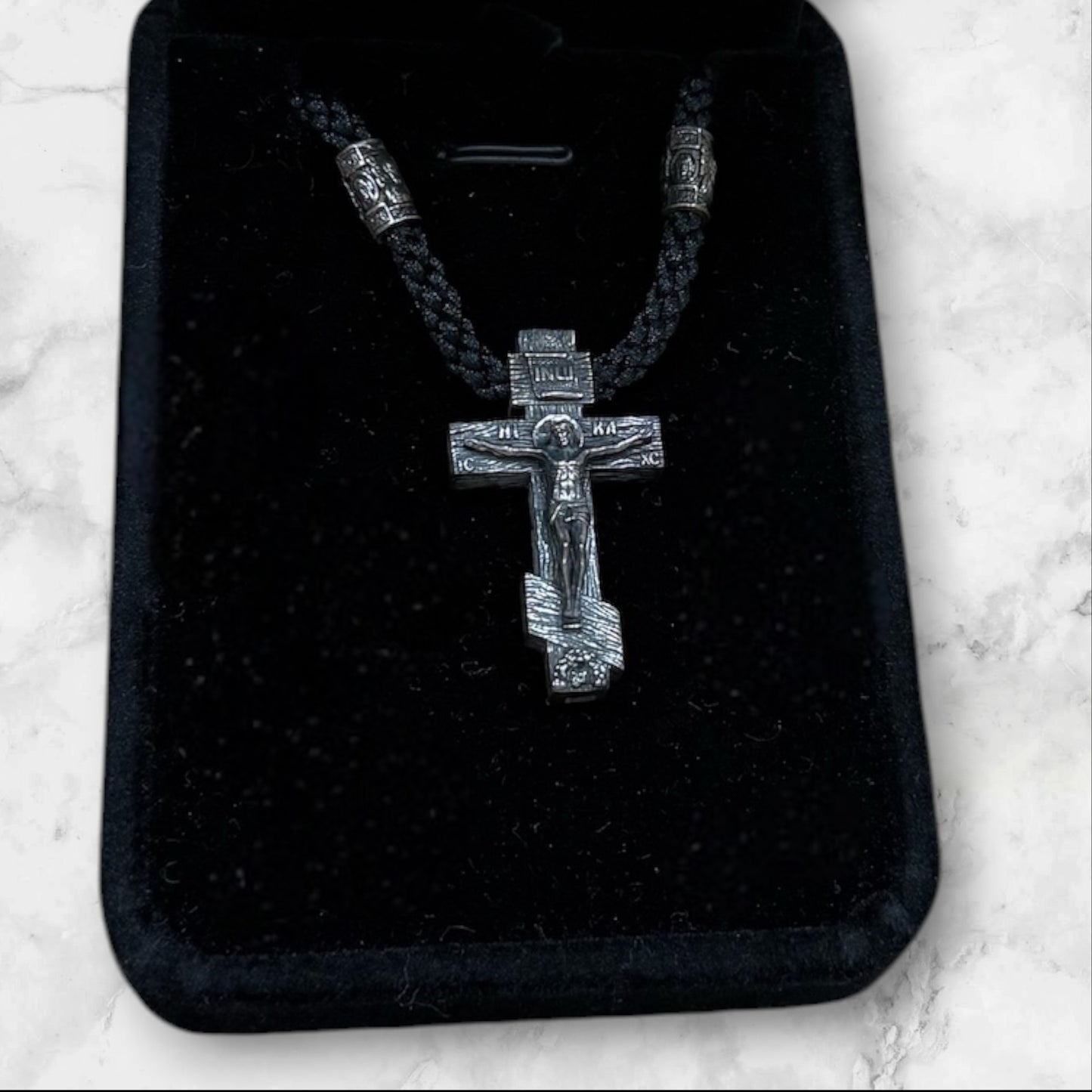 Orthodox crucifix pendant with braided black cord displayed in a gift box