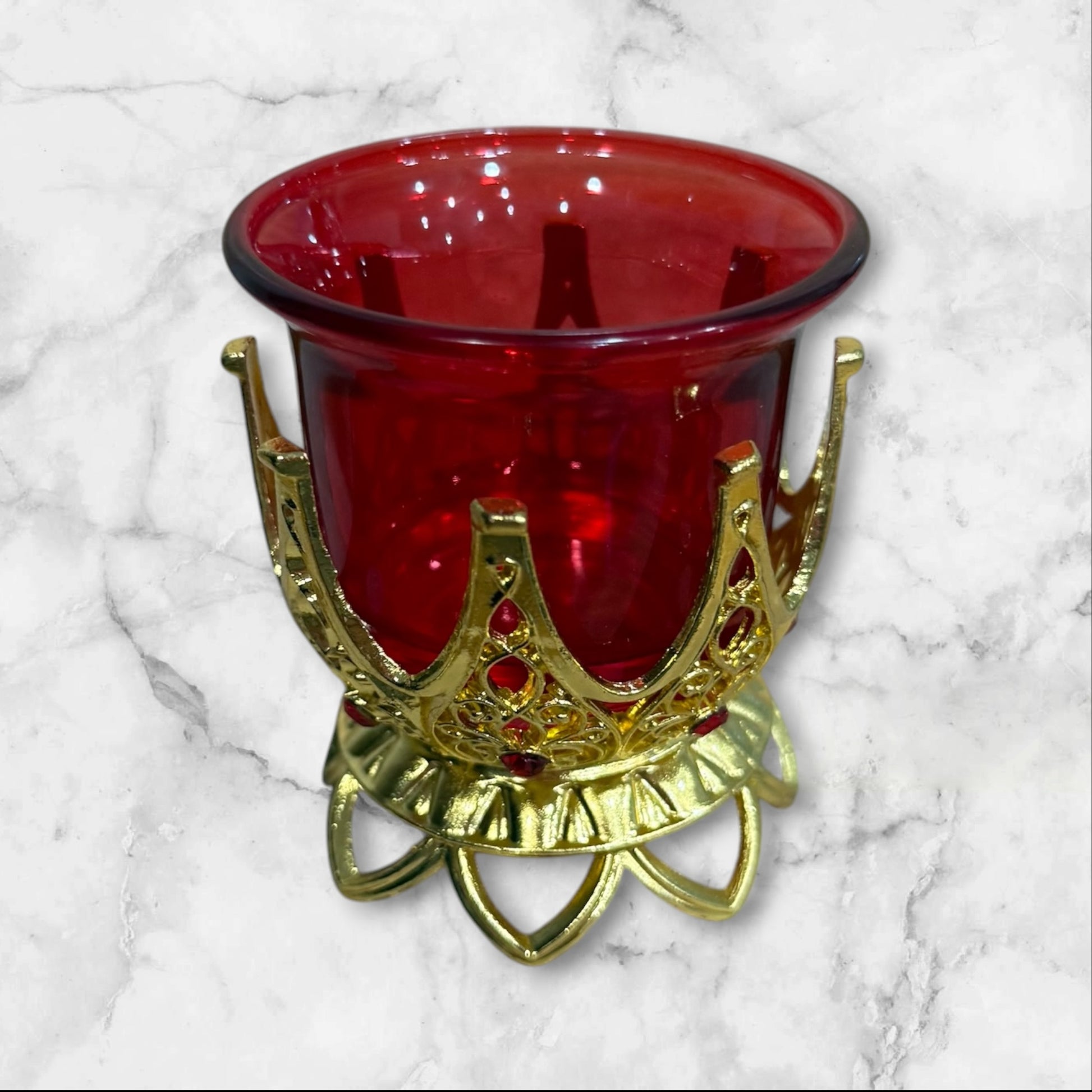 Orthodox ruby red glass votive candle holder with decorative gold-tone filigree base for a home prayer corner.