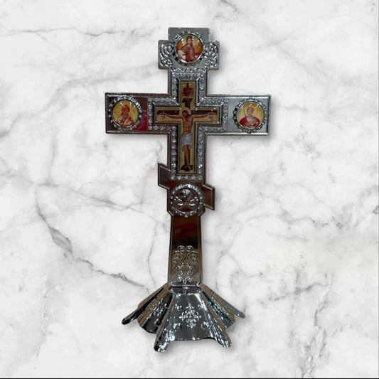 Silver Orthodox standing crucifix with icon accents on a decorative freestanding base for a home prayer corner
