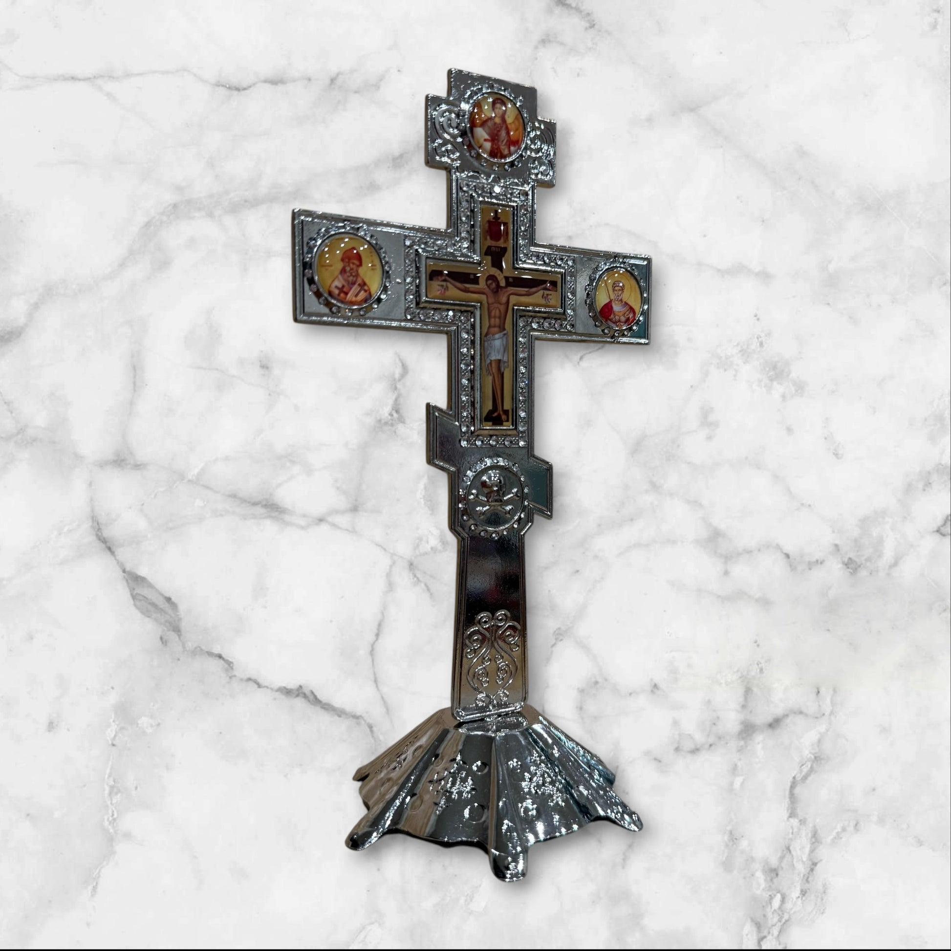 Silver Orthodox standing crucifix with icon accents on a decorative freestanding base for a home prayer corner